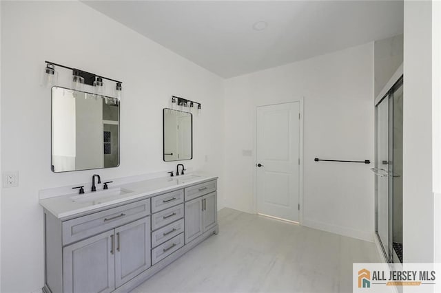 bathroom with double vanity, a sink, and a shower with door