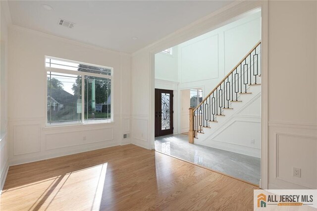 entryway featuring ornamental molding, wood-type flooring, and a wealth of natural light