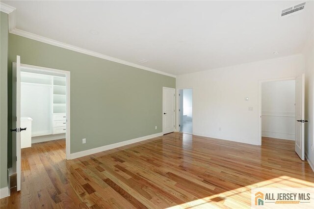 spare room featuring ornamental molding and light wood-type flooring