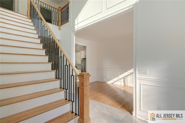 staircase featuring wood-type flooring and a high ceiling