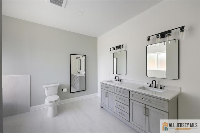 full bath with toilet, baseboards, visible vents, and a sink