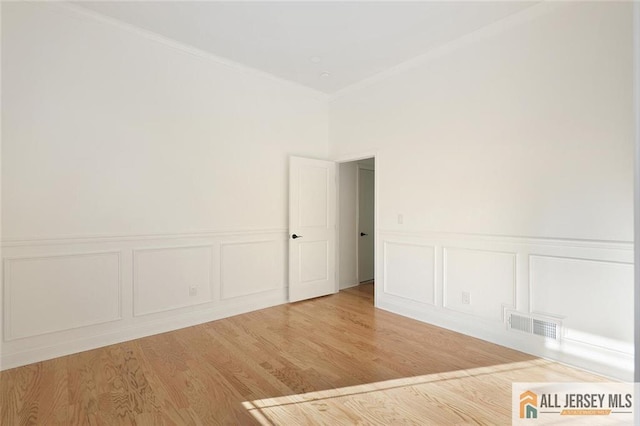 unfurnished room featuring ornamental molding, wood finished floors, and visible vents