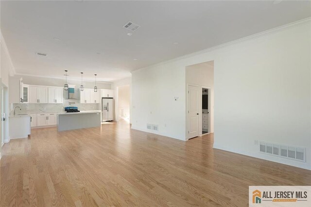 unfurnished living room featuring ornamental molding, light hardwood / wood-style floors, and sink