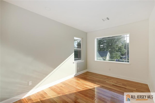 empty room featuring visible vents, baseboards, and wood finished floors