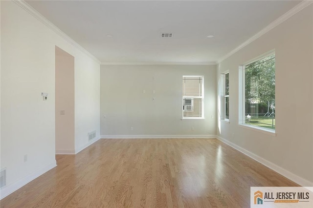 spare room with light wood-type flooring, visible vents, and crown molding