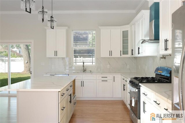 kitchen featuring appliances with stainless steel finishes, sink, wall chimney range hood, and white cabinets