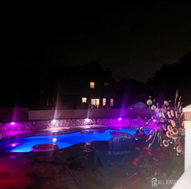 pool at twilight featuring a jacuzzi and an outdoor pool