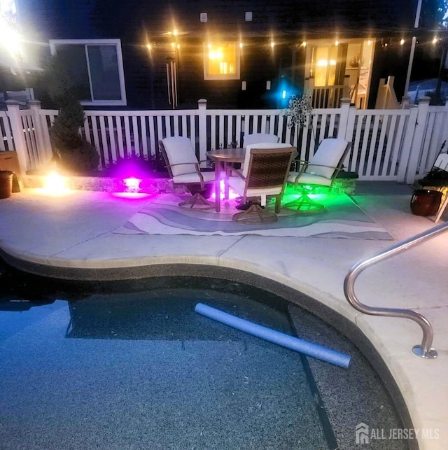 pool at night with a patio and an outdoor pool