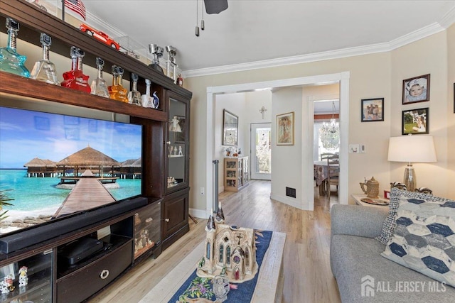 living room with light wood-style floors, ornamental molding, and baseboards