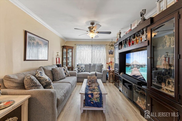 living room featuring a ceiling fan, ornamental molding, and light wood-style flooring
