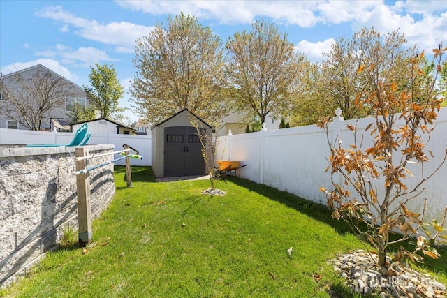 view of yard with an outbuilding, a fenced backyard, and a storage unit