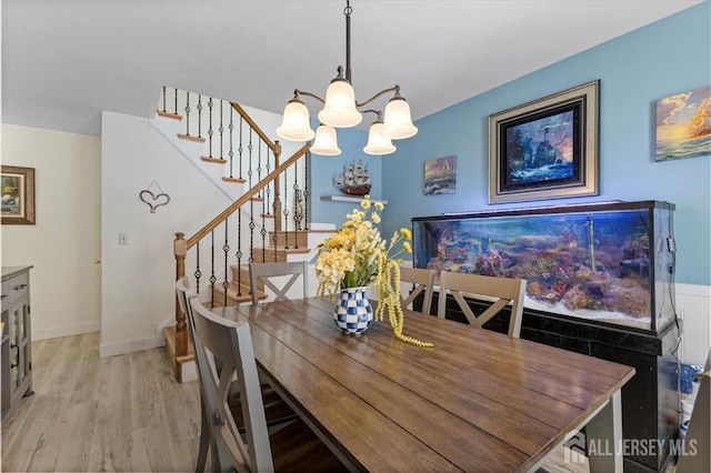 dining room featuring baseboards, a chandelier, stairway, and light wood-type flooring