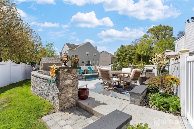 view of patio / terrace with an outbuilding, a fenced backyard, outdoor dining space, and a storage unit