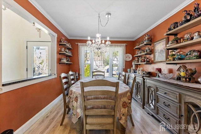 dining area featuring an inviting chandelier, ornamental molding, and light wood finished floors