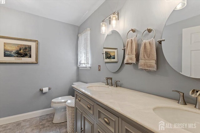 bathroom with double vanity, a sink, baseboards, and toilet