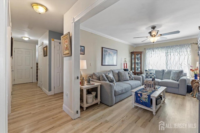 living room with baseboards, ceiling fan, ornamental molding, and light wood-style flooring