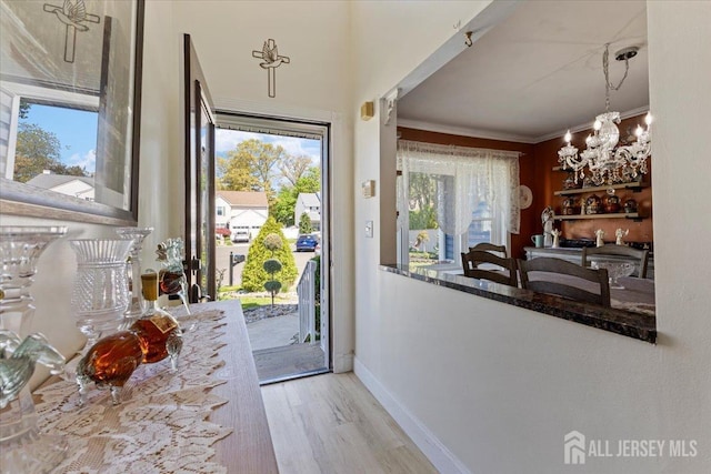 doorway to outside featuring a healthy amount of sunlight, baseboards, ornamental molding, and wood finished floors