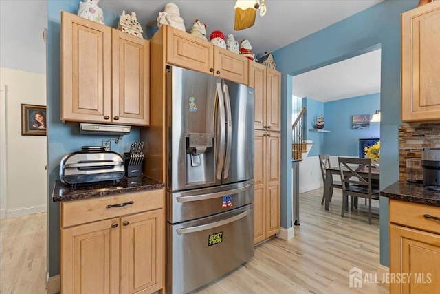 kitchen featuring stainless steel refrigerator with ice dispenser, light brown cabinetry, baseboards, dark stone counters, and light wood-style flooring