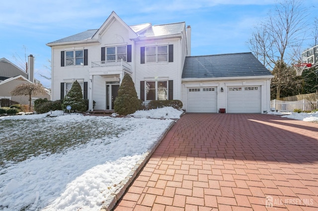 view of front facade featuring decorative driveway, an attached garage, and a balcony