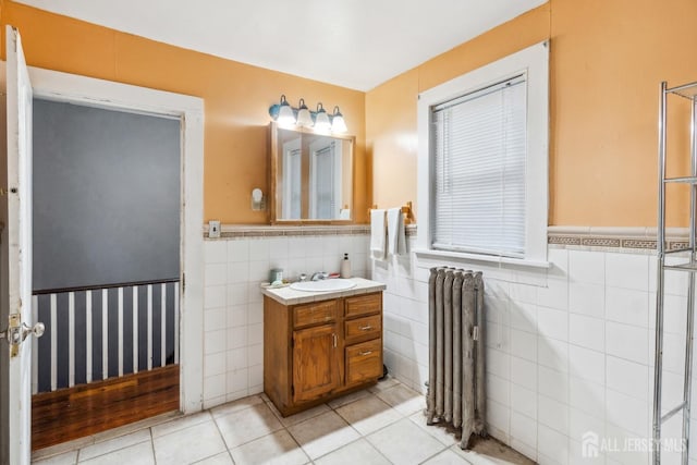 bathroom featuring tile walls, vanity, radiator heating unit, and tile patterned floors