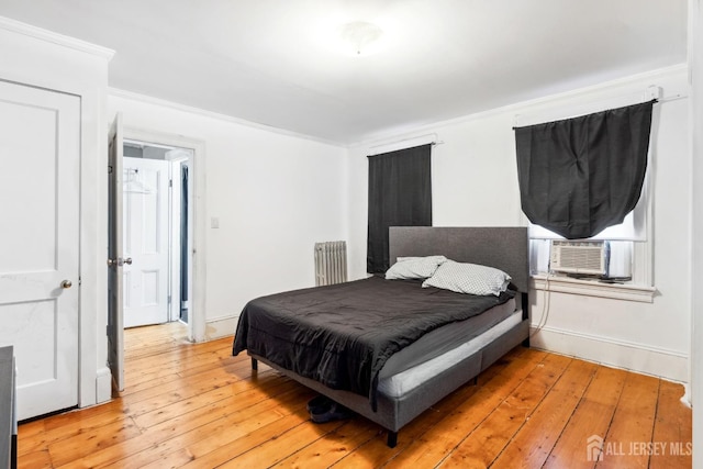 bedroom featuring cooling unit, radiator heating unit, light hardwood / wood-style flooring, and ornamental molding