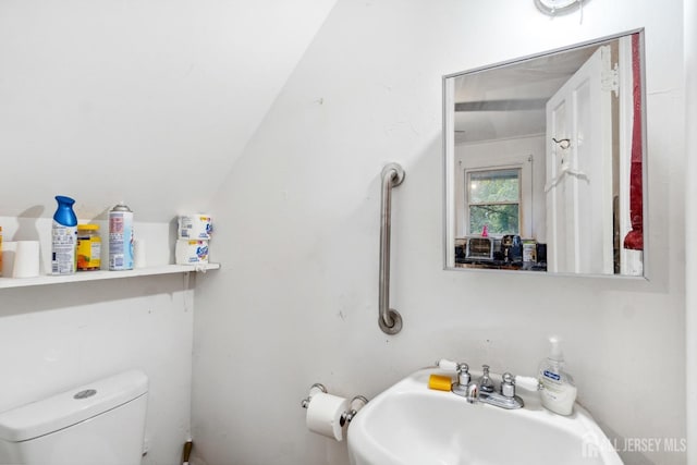 bathroom with vaulted ceiling, toilet, and sink