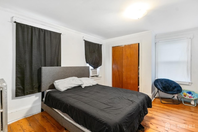 bedroom featuring crown molding, cooling unit, hardwood / wood-style flooring, and a closet