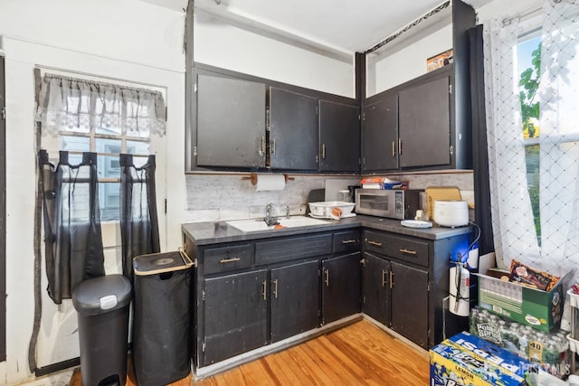 kitchen with tasteful backsplash, sink, and light wood-type flooring