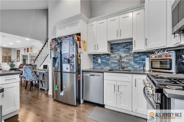 10 Buttonwood Dr, Old Bridge, NJ 08857 - kitchen with appliances with stainless steel finishes, a sink, dark countertops, light wood-type flooring, and backsplash