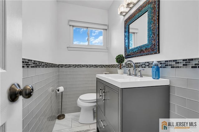 10 Buttonwood Dr, Old Bridge, NJ 08857 - bathroom featuring tile walls, vanity, toilet, marble look tile flooring, and a wainscoted wall