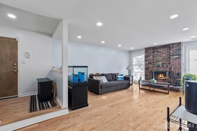 living room with light hardwood / wood-style floors, a brick fireplace, and a wealth of natural light