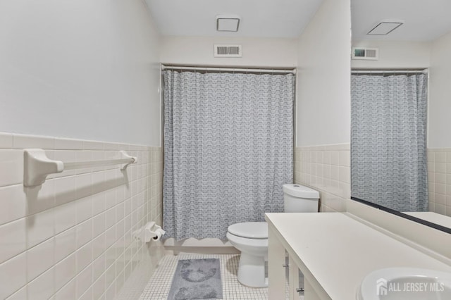 bathroom featuring tile walls, vanity, tile patterned floors, toilet, and walk in shower