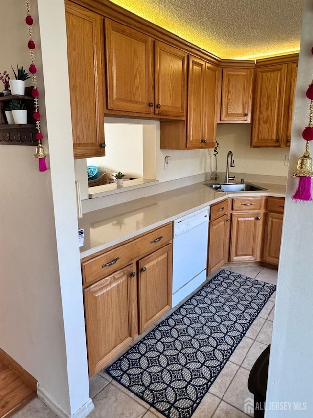 kitchen with light countertops, white dishwasher, a textured ceiling, and a sink