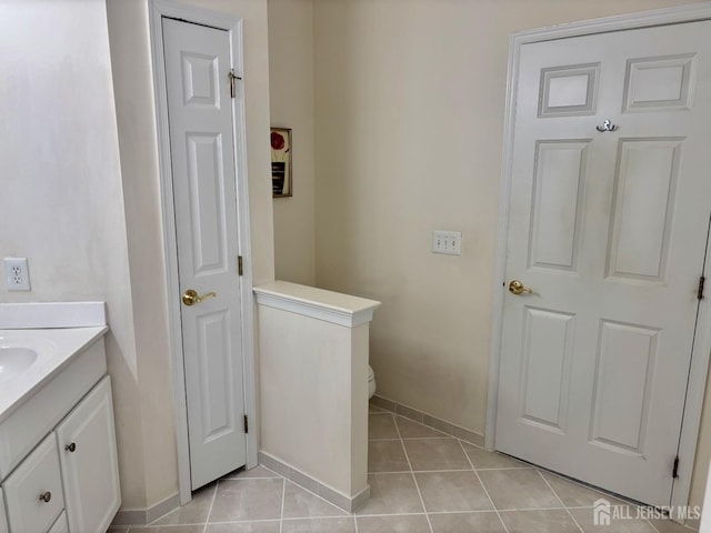 bathroom with baseboards, tile patterned floors, toilet, and vanity