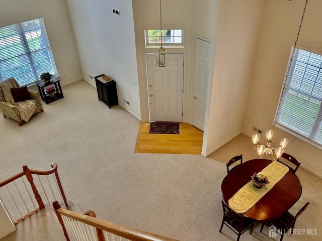 foyer featuring an inviting chandelier, carpet, visible vents, and a wealth of natural light