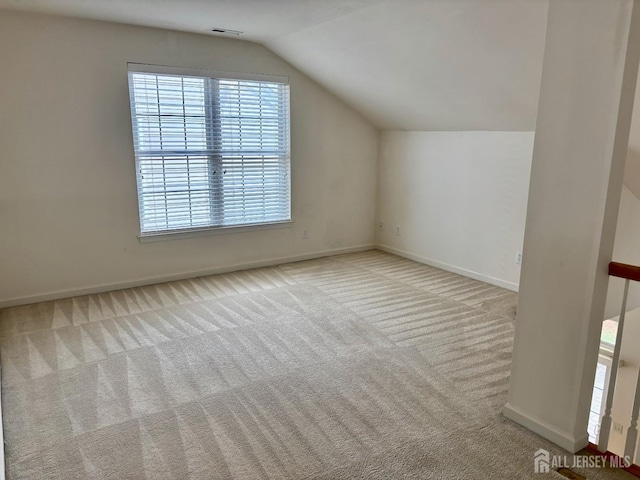 additional living space with baseboards, visible vents, carpet floors, and vaulted ceiling