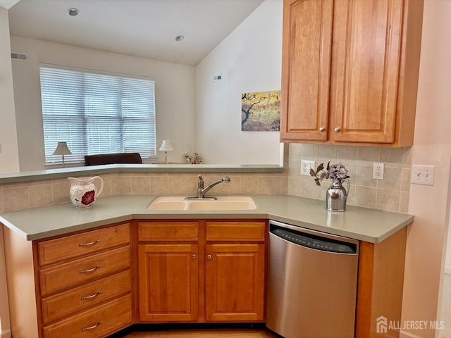 kitchen featuring tasteful backsplash, stainless steel dishwasher, a sink, visible vents, and light countertops