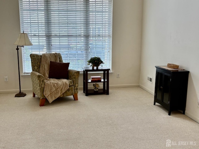 living area with visible vents, baseboards, and carpet floors