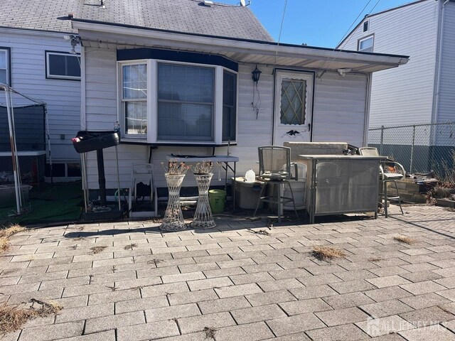 back of property featuring a patio area, roof with shingles, and fence