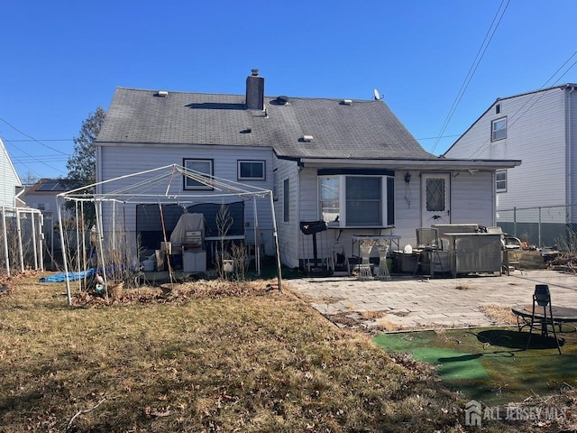 rear view of property with a patio area, a chimney, and fence