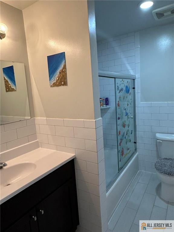3205 Hana Rd, Edison, NJ 08817 - full bathroom featuring tile walls, vanity, combined bath / shower with glass door, tile patterned flooring, and a wainscoted wall