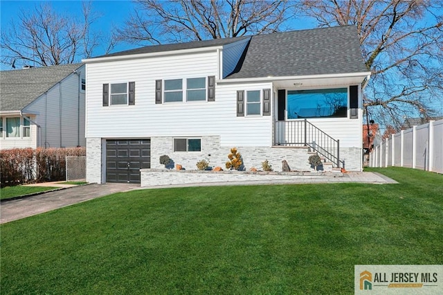 tri-level home with fence, driveway, roof with shingles, a front lawn, and a garage