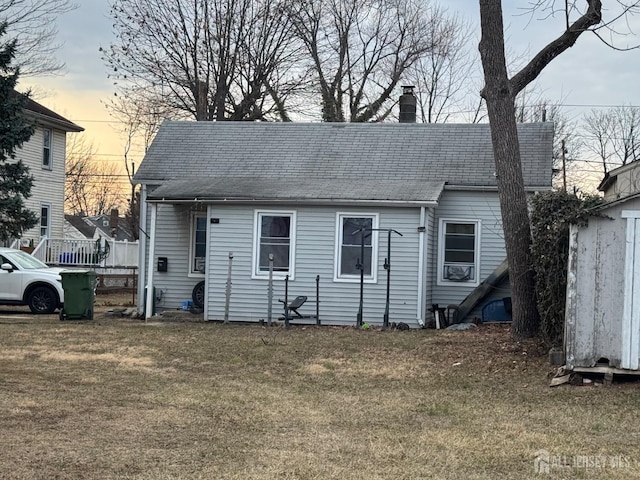 rear view of property with a yard, an outbuilding, and a chimney