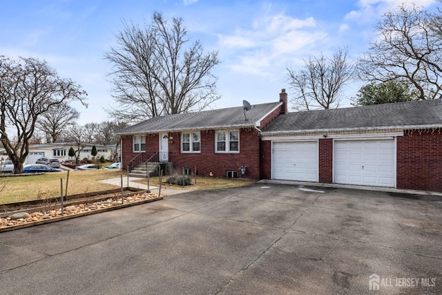 ranch-style house featuring aphalt driveway, brick siding, a garage, and a chimney