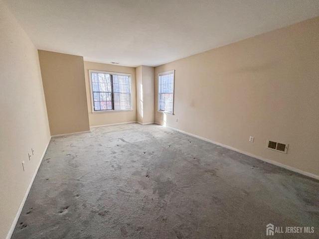 unfurnished room featuring baseboards, visible vents, and carpet