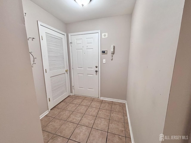 doorway featuring baseboards and light tile patterned flooring