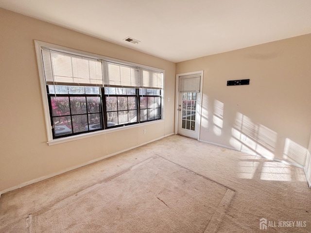 carpeted spare room with visible vents, baseboards, and a healthy amount of sunlight