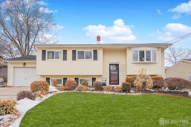 bi-level home featuring a garage, driveway, a front lawn, and a chimney