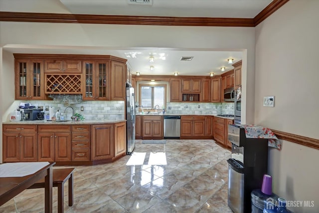 kitchen with tasteful backsplash, sink, stainless steel appliances, and ornamental molding