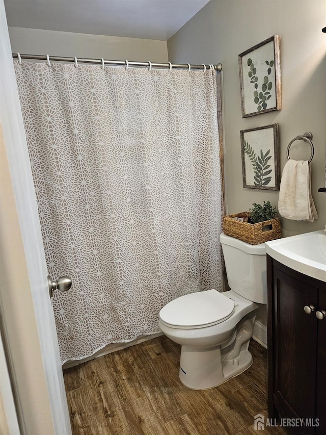 bathroom featuring toilet, a shower with shower curtain, vanity, and wood finished floors